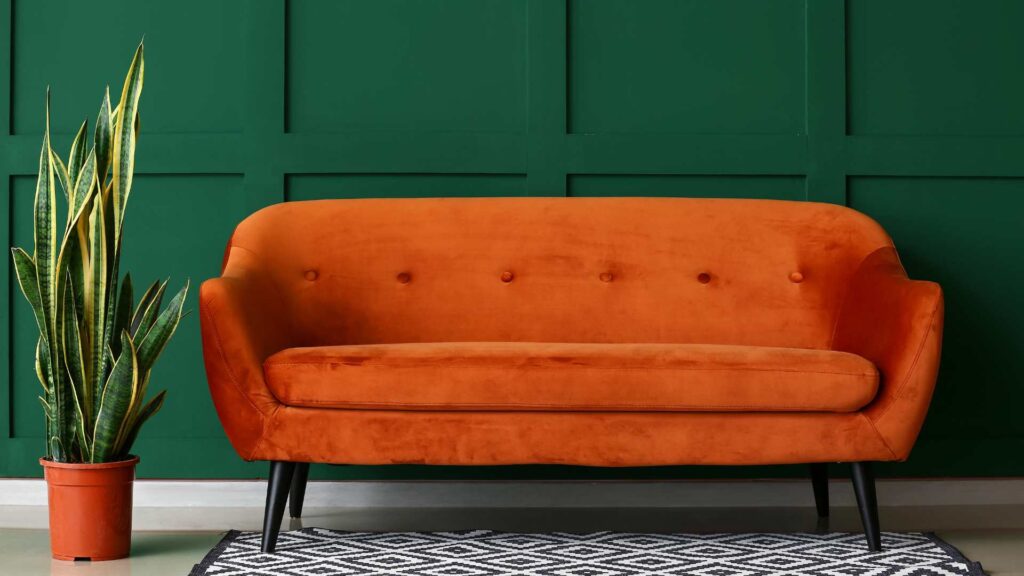 Canapé orange sur un mur vert foncé 
